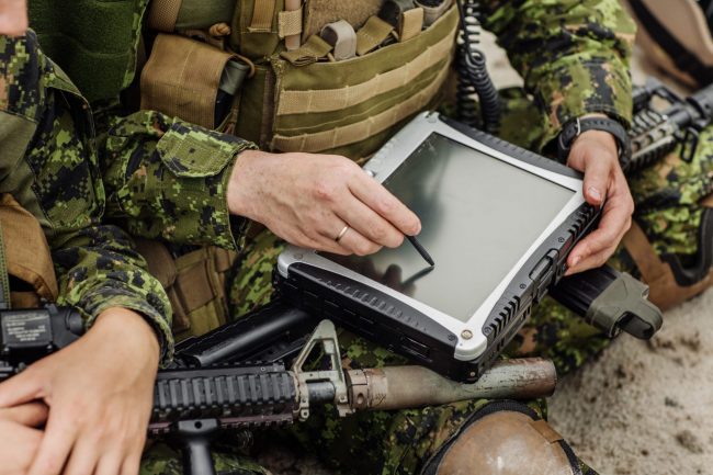 Closeup of soldier with tablet illustrates blog "What Is the Difference Between CMMC and NIST SP 800-171? "