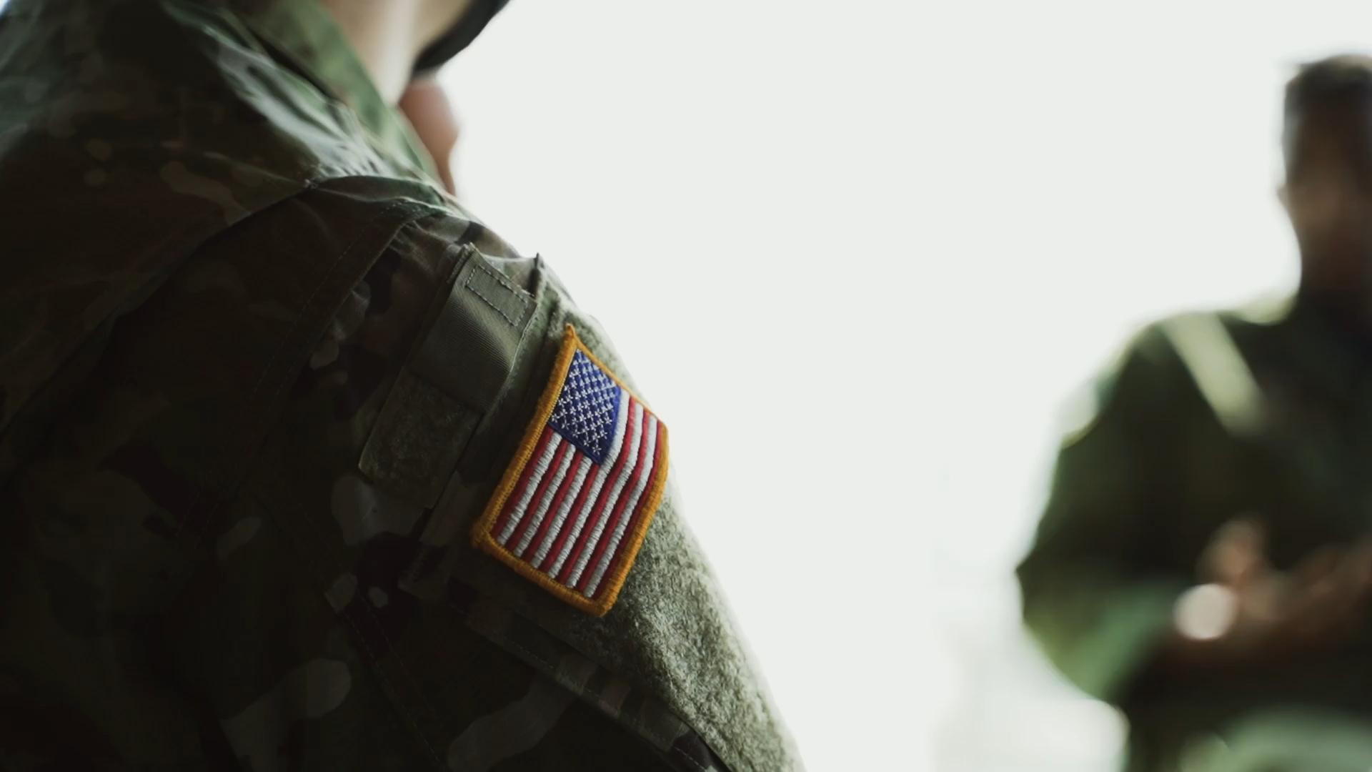 Soldier seen from behind with an American flag patch on the shoulder.